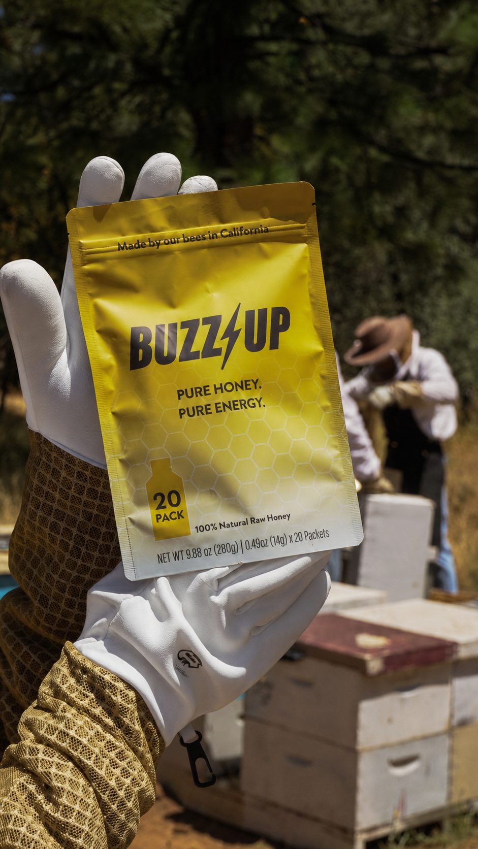 Gloved beekeeper holding a Buzz Up bag in front of the hives