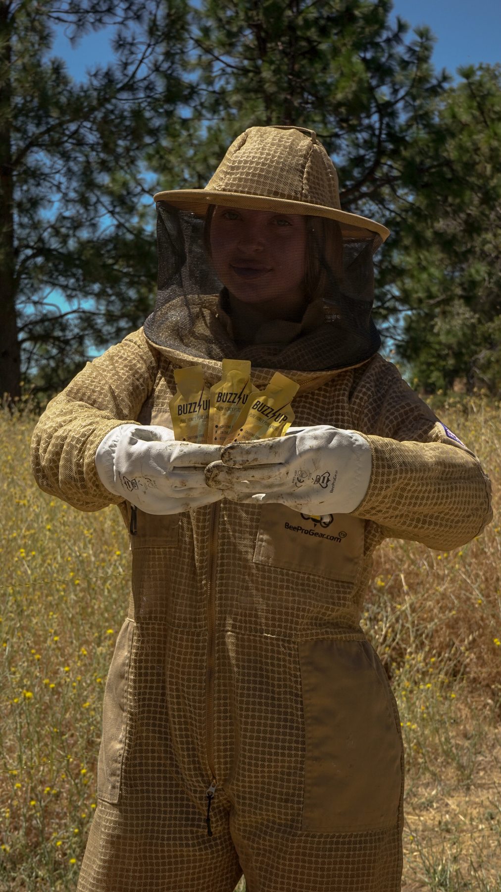 Beekeeper in a full suit holding Buzz Up packets