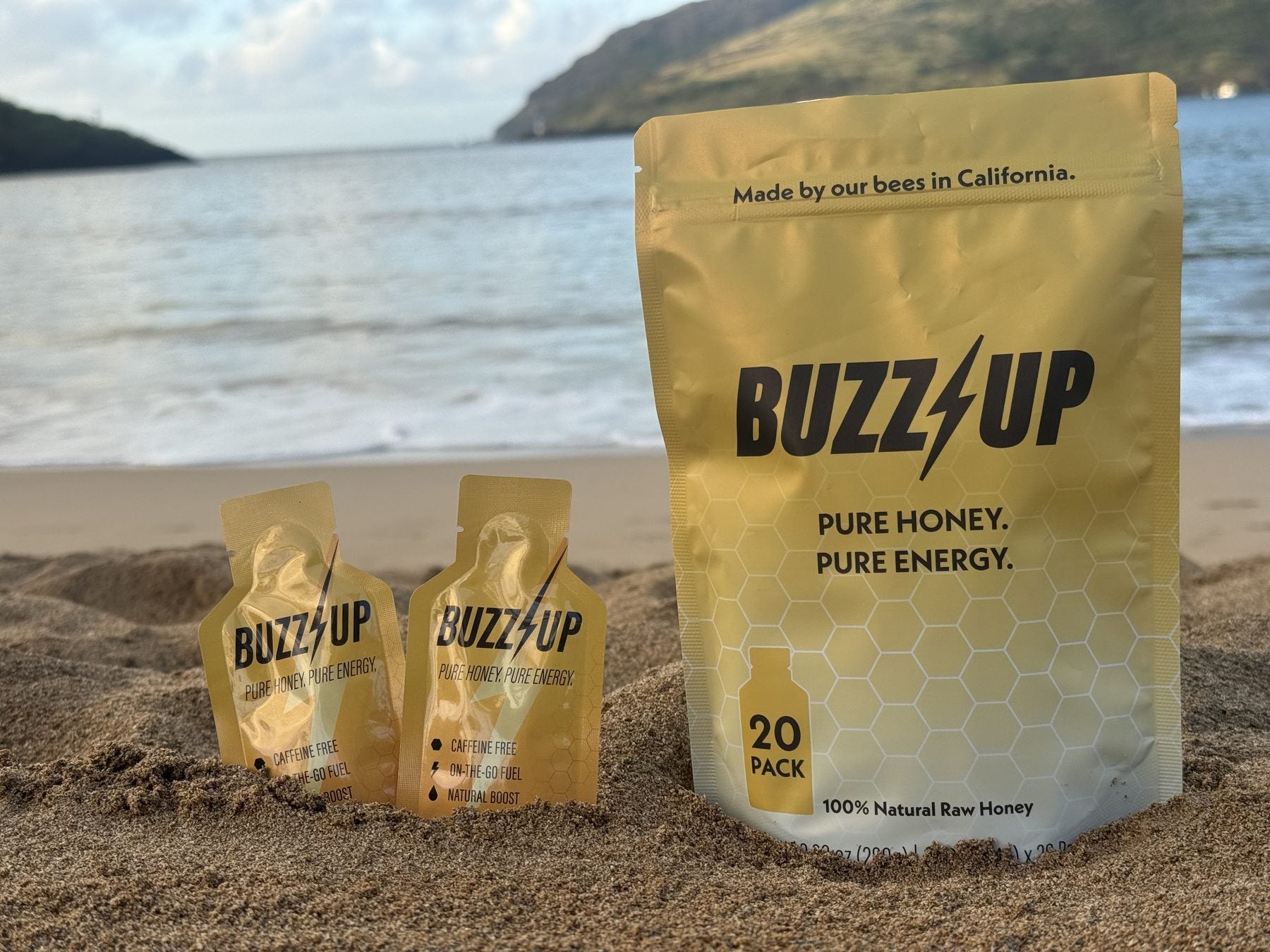 Buzz Up 20-pack bag and packets in the sand on a beach